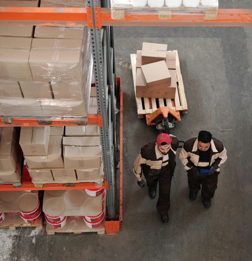 High angle view of warehouse workers organizing and preparing shipments with boxes and pallets.